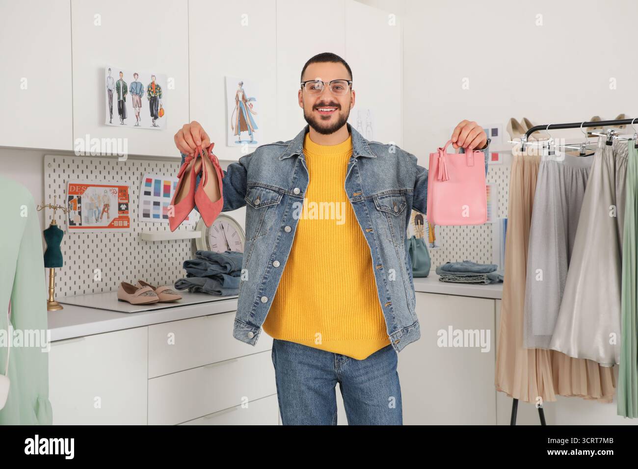 Stilista maschile felice con tacchi alti alla moda e borsa da lavoro in studio Foto Stock