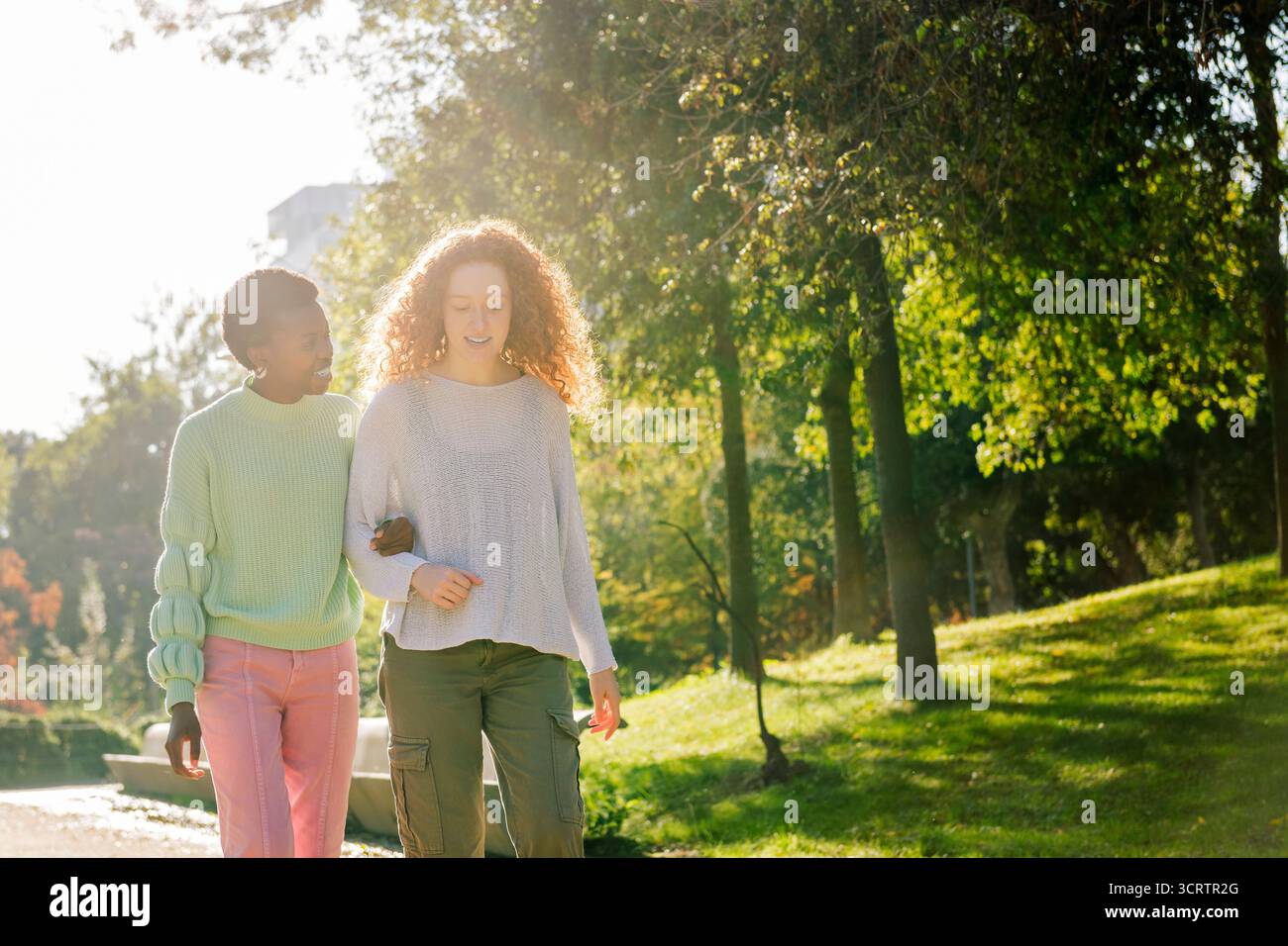 due giovani donne sorridono e parlano durante una passeggiata Foto Stock