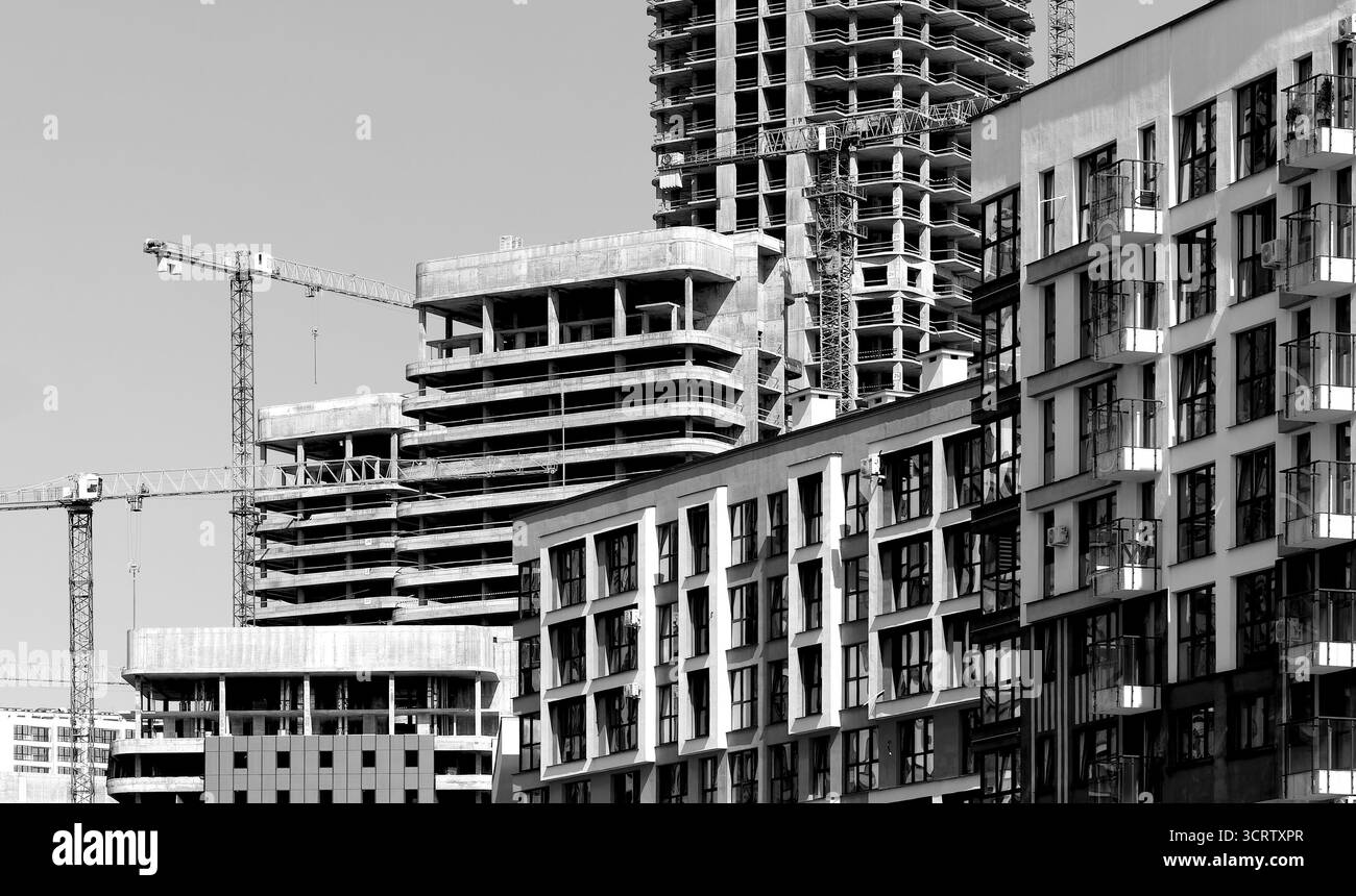 Cantiere di una moderna torre alta nel quartiere urbano in via di sviluppo. Struttura in calcestruzzo non finita con gru, struttura in acciaio e lavori di facciata. C Foto Stock