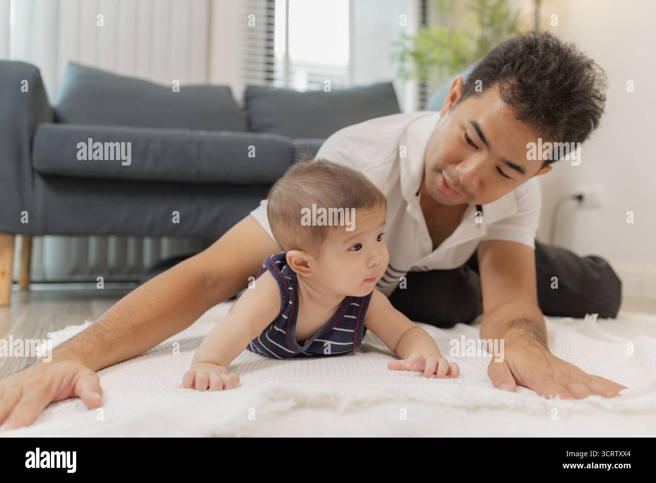 Un padre trascorre del tempo di qualità con il suo bambino, giocando e legando attraverso una cura delicata e momenti divertenti su un tappetino morbido. Il bambino esplora il tempo del pancino e la pa Foto Stock