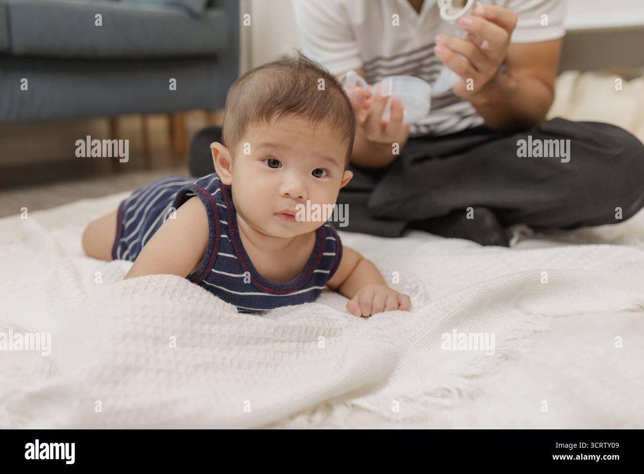 Un padre trascorre del tempo di qualità con il suo bambino, giocando e legando attraverso una cura delicata e momenti divertenti su un tappetino morbido. Il bambino esplora il tempo del pancino e la pa Foto Stock