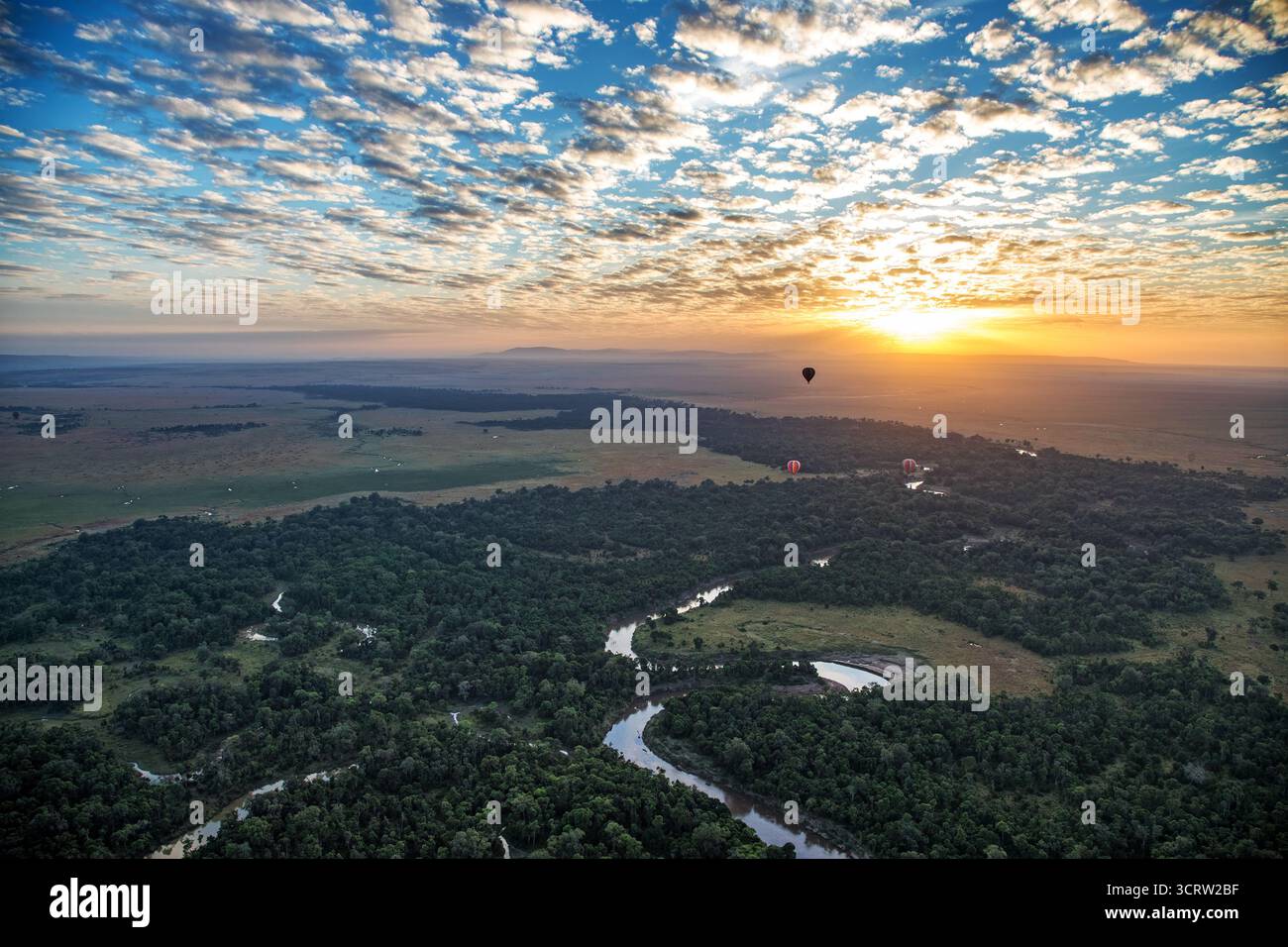 Si innalza sopra il fiume Mara mentre serpeggia attraverso il paesaggio del Masai Mara. Giro in mongolfiera all'alba. Kenya, Africa. Foto Stock