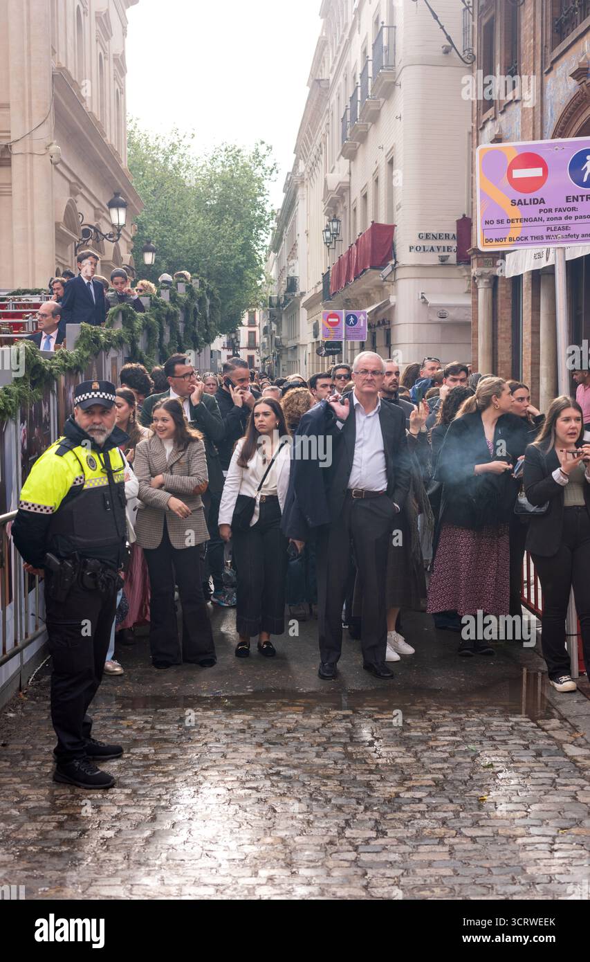 Un ufficiale di polizia municipale a Siviglia, in Spagna, si trova di fronte alla folla durante le celebrazioni della settimana Santa. Foto Stock