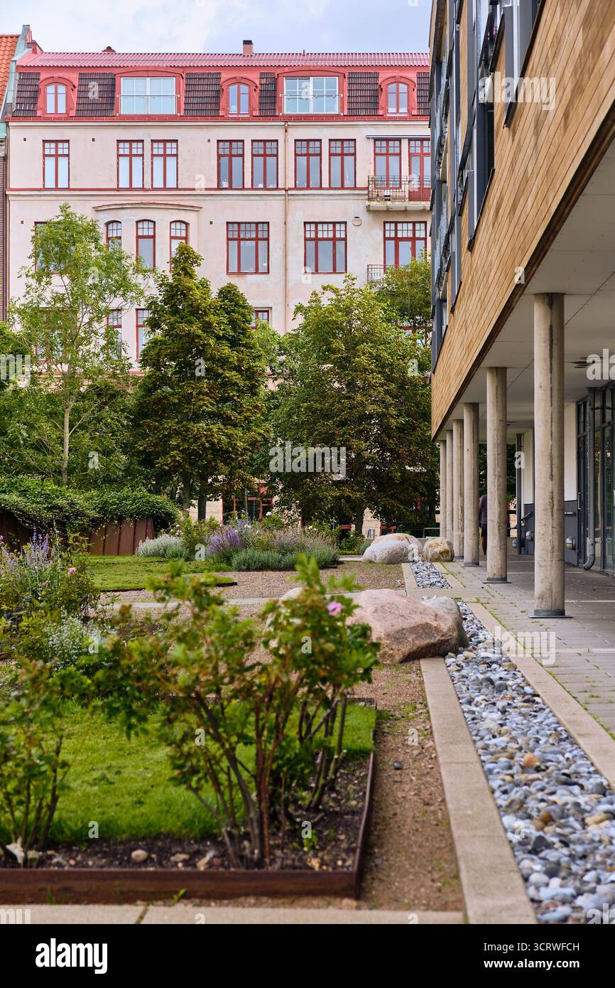 Helsingborg, Svezia; 12 agosto 2025: Cortile paesaggistico con verde e moderna architettura residenziale che illustra lo sviluppo urbano sostenibile Foto Stock