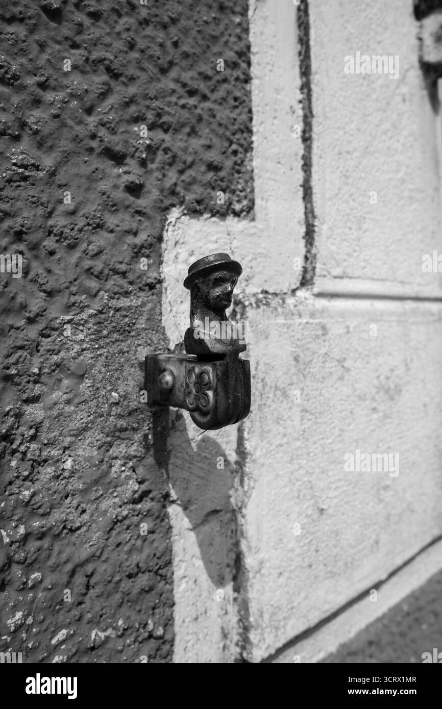 Un'affascinante scultura di busto in miniatura con una macchina fotografica, applicata su una parete testurizzata, che cattura l'essenza dell'arte urbana vintage in bianco e nero. Foto Stock