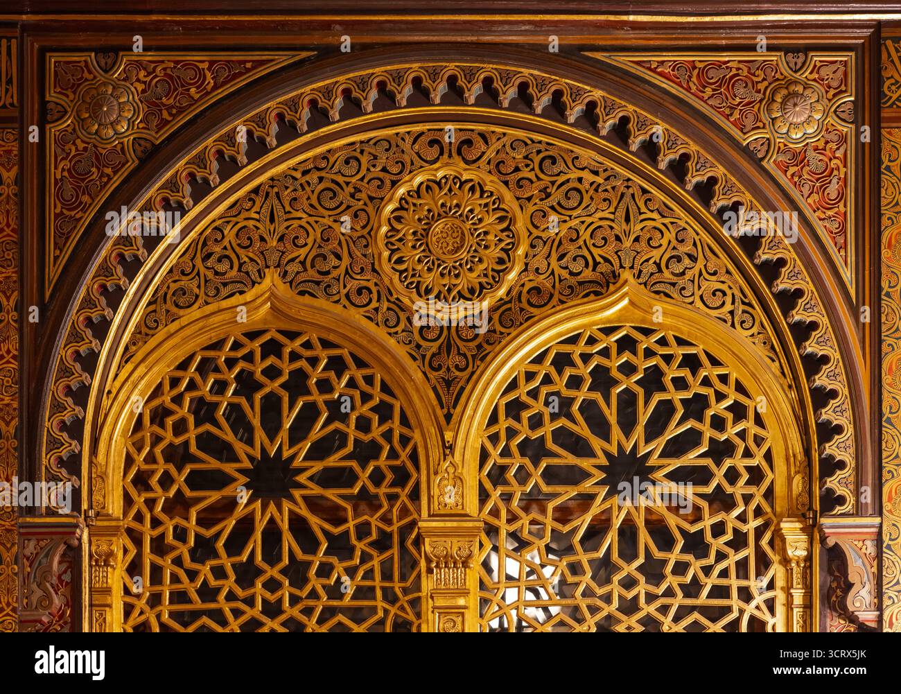 Arcata dorata con pannelli geometrici a reticolo, motivi arabeschi decorati e dettagli in legno intagliato. Un lussuoso esempio di artisti architettonici islamici Foto Stock