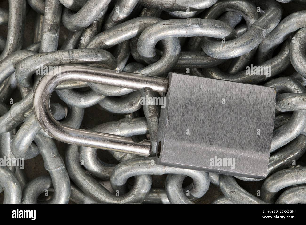 Lucchetto color argento sbloccato su un mucchio di catene concetto di sicurezza industriale STILL Life. Foto Stock