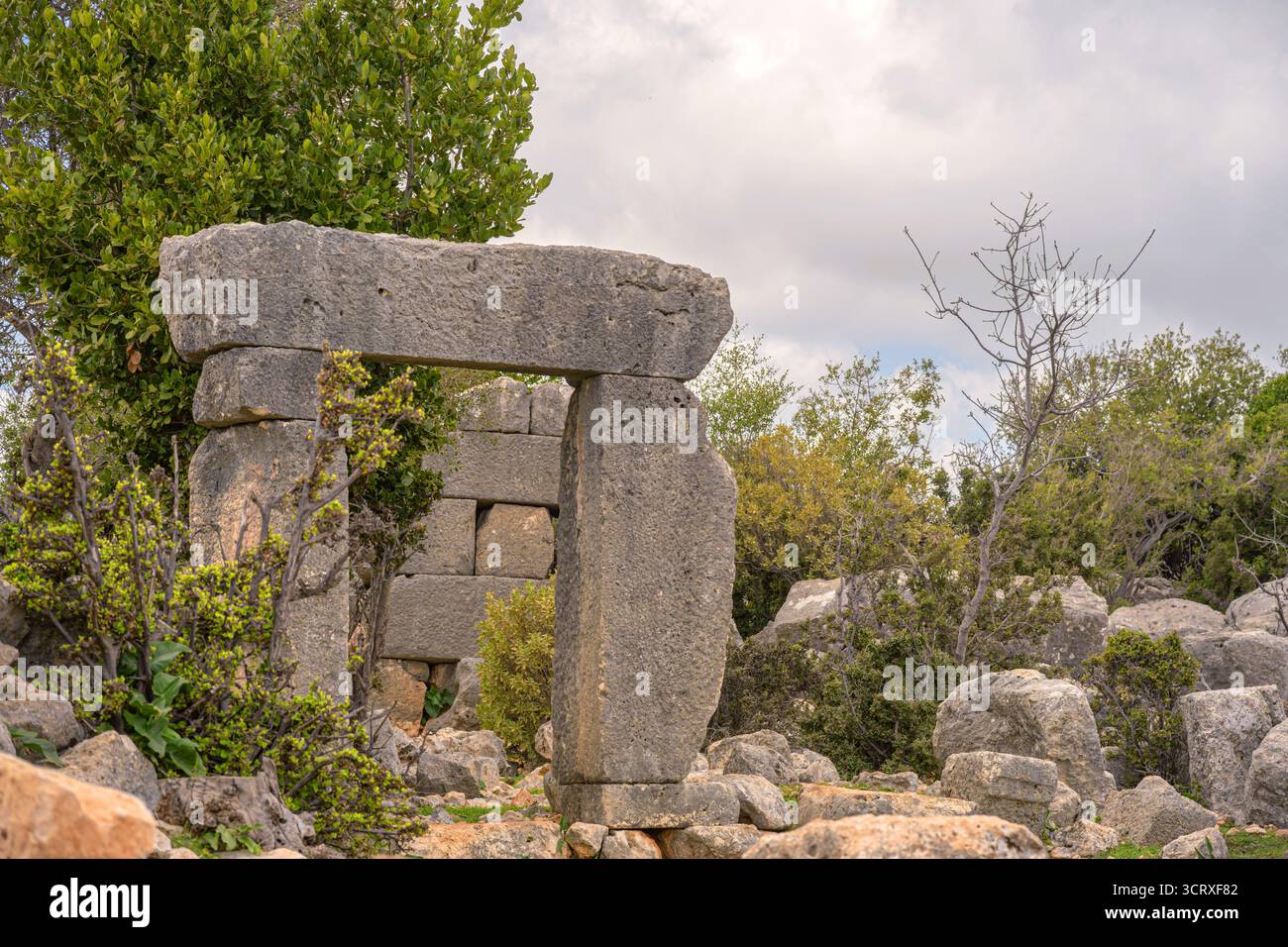 Un'antica porta in pietra sorge tra rovine sparse e fitta vegetazione naturale. Accennare a una civiltà perduta da tempo. Ideale per l'uso in viaggio e. Foto Stock