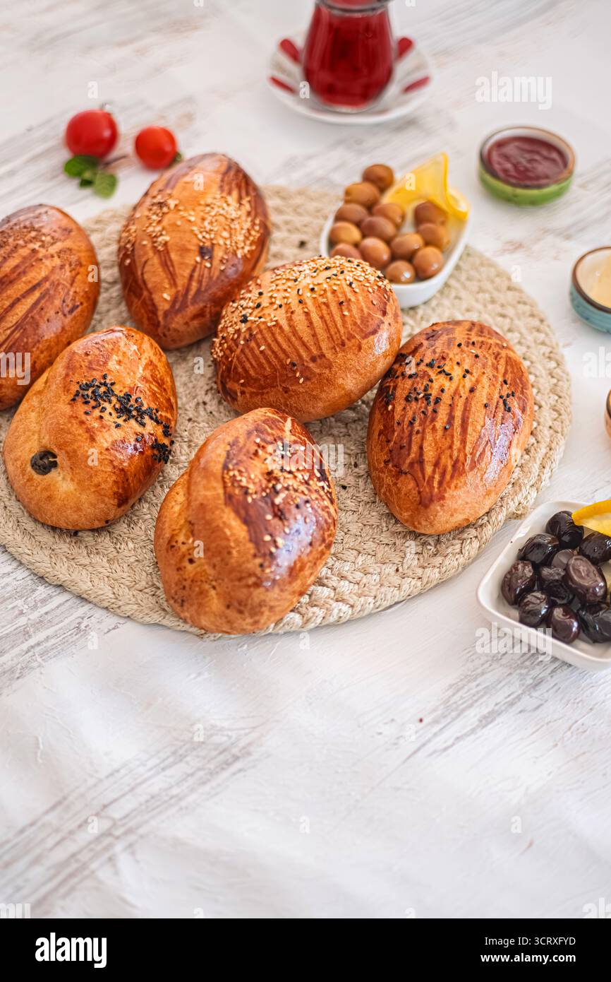 Pasticcini appena sfornati con accompagnamenti. Selezione di dolci appena sfornati disposti su un tappeto intrecciato. Messa a fuoco selettiva. Foto Stock