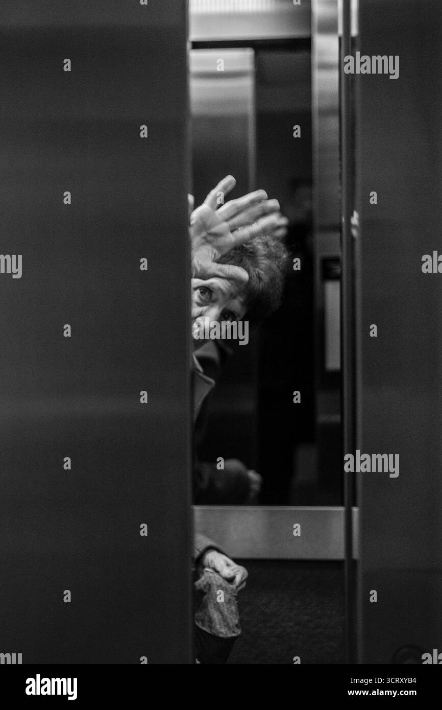 Signora anziana, salutando dalla porta dell'ascensore di chiusura, Foto Stock