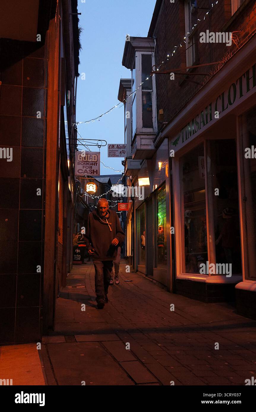 Uomo che cammina lungo Emery Lane al crepuscolo in città Foto Stock