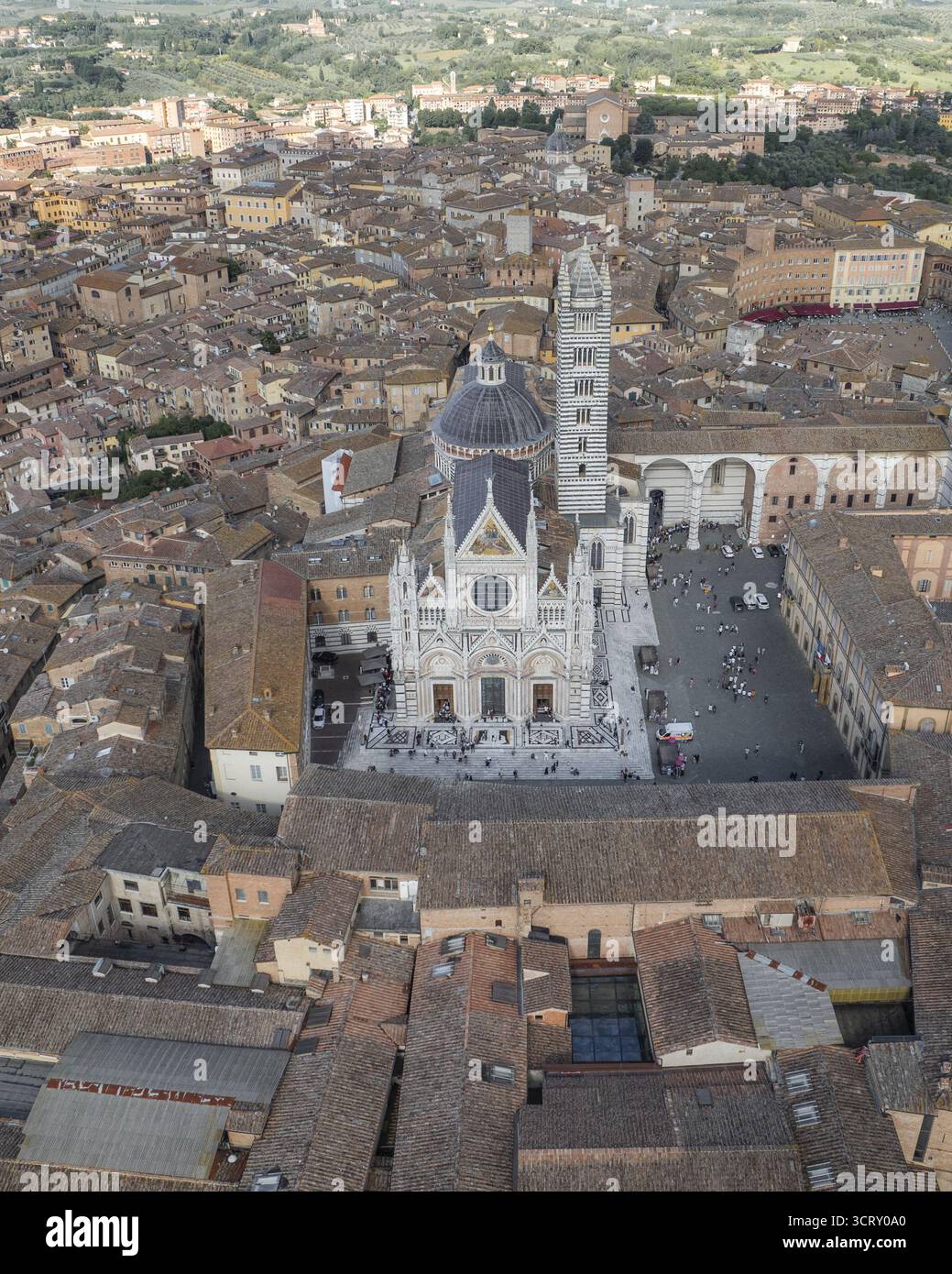 La vista aerea del Duomo di Siena si erge maestosamente, con la sua facciata in marmo bianco che contrasta con i caldi tetti in terracotta, Siena, Toscana, Ital Foto Stock