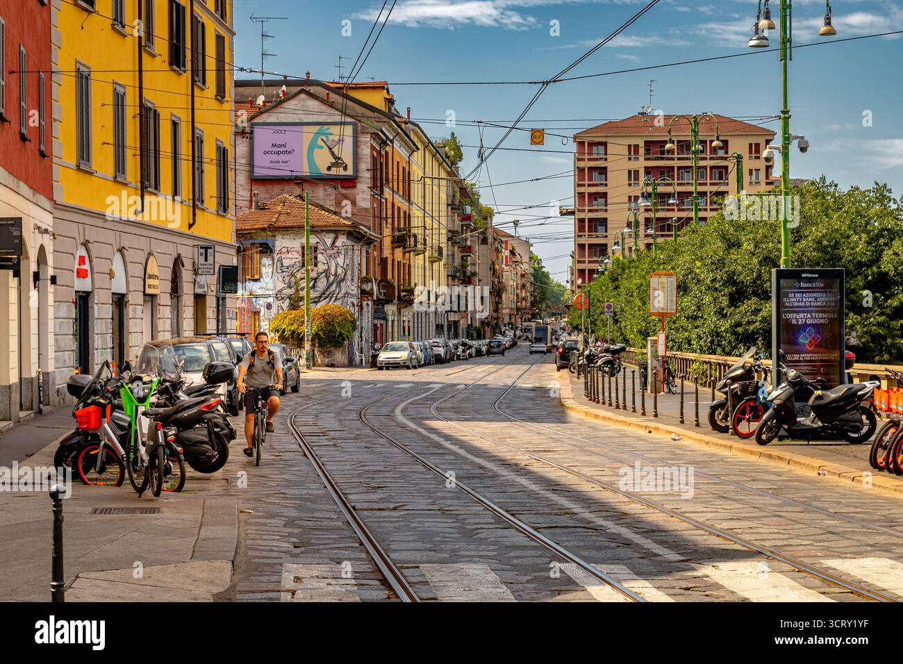 Un uomo che pedala lungo Viale Gorizia nel quartiere dei Navigli, Milano, Italia Foto Stock