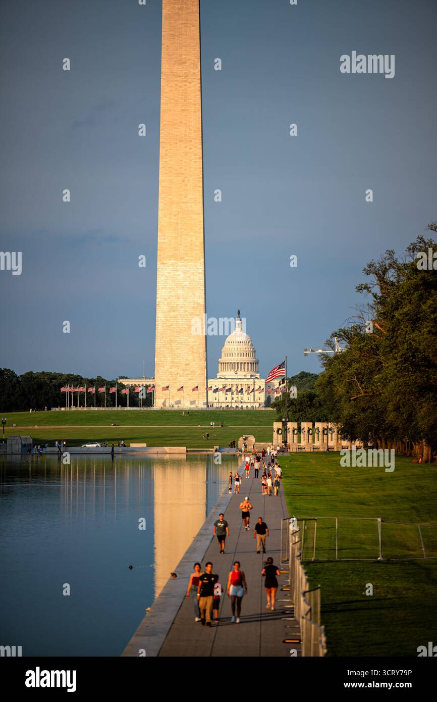 Washington Monument e Capitol Building National Mall Washington DC // WASHINGTON DC - il Washington Monument e il Campidoglio degli Stati Uniti sono visibili attraverso la piscina riflettente sul National Mall durante una serata limpida. I visitatori camminano lungo il sentiero adiacente al Memoriale della seconda Guerra Mondiale, visibile sulla destra. Il Washington Monument, un obelisco che commemora George Washington, è alto 169,29 metri (555 piedi 5 1/8 pollici) ed è stato completato nel 1884. Il Campidoglio degli Stati Uniti è la sede del Congresso degli Stati Uniti. Il National Mall è un parco nazionale gestito dal National Park Service Foto Stock