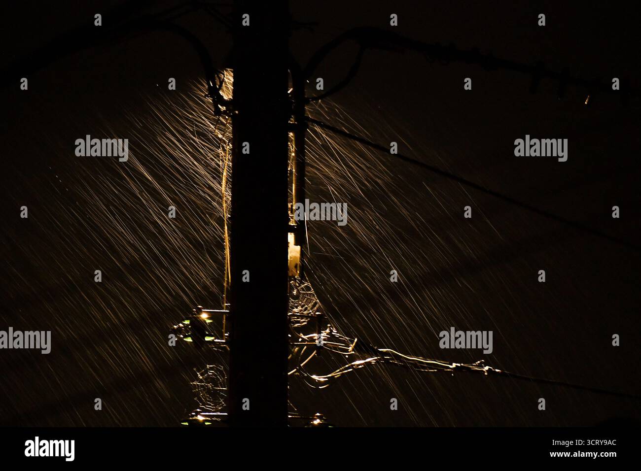 Pioggia intensa che cade nell'illuminazione atmosferica contro un lampione del telegrafo. Foto Stock