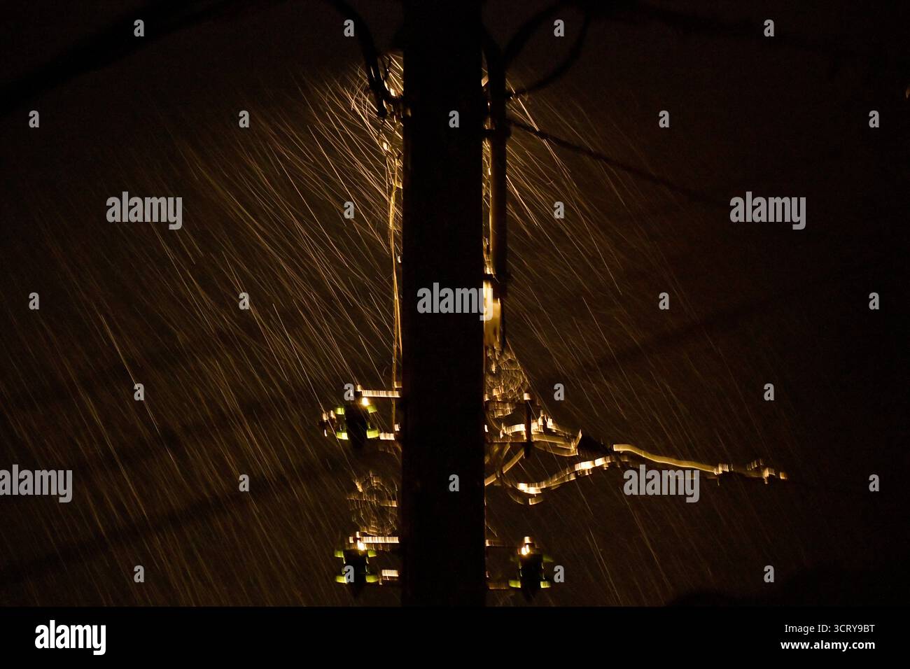 Pioggia intensa che cade nell'illuminazione atmosferica contro un lampione del telegrafo. Foto Stock