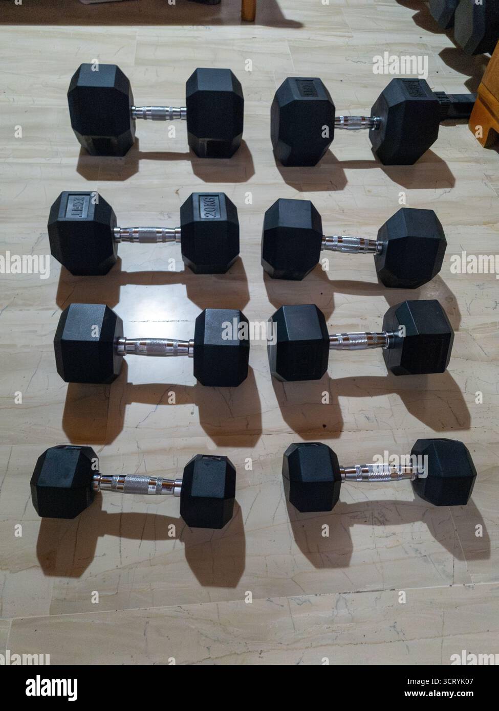 Set di manubri esagonali neri disposti in file su un pavimento per un allenamento in palestra. Pesi pesanti per fitness, bodybuilding, crossfit e Strength traini Foto Stock