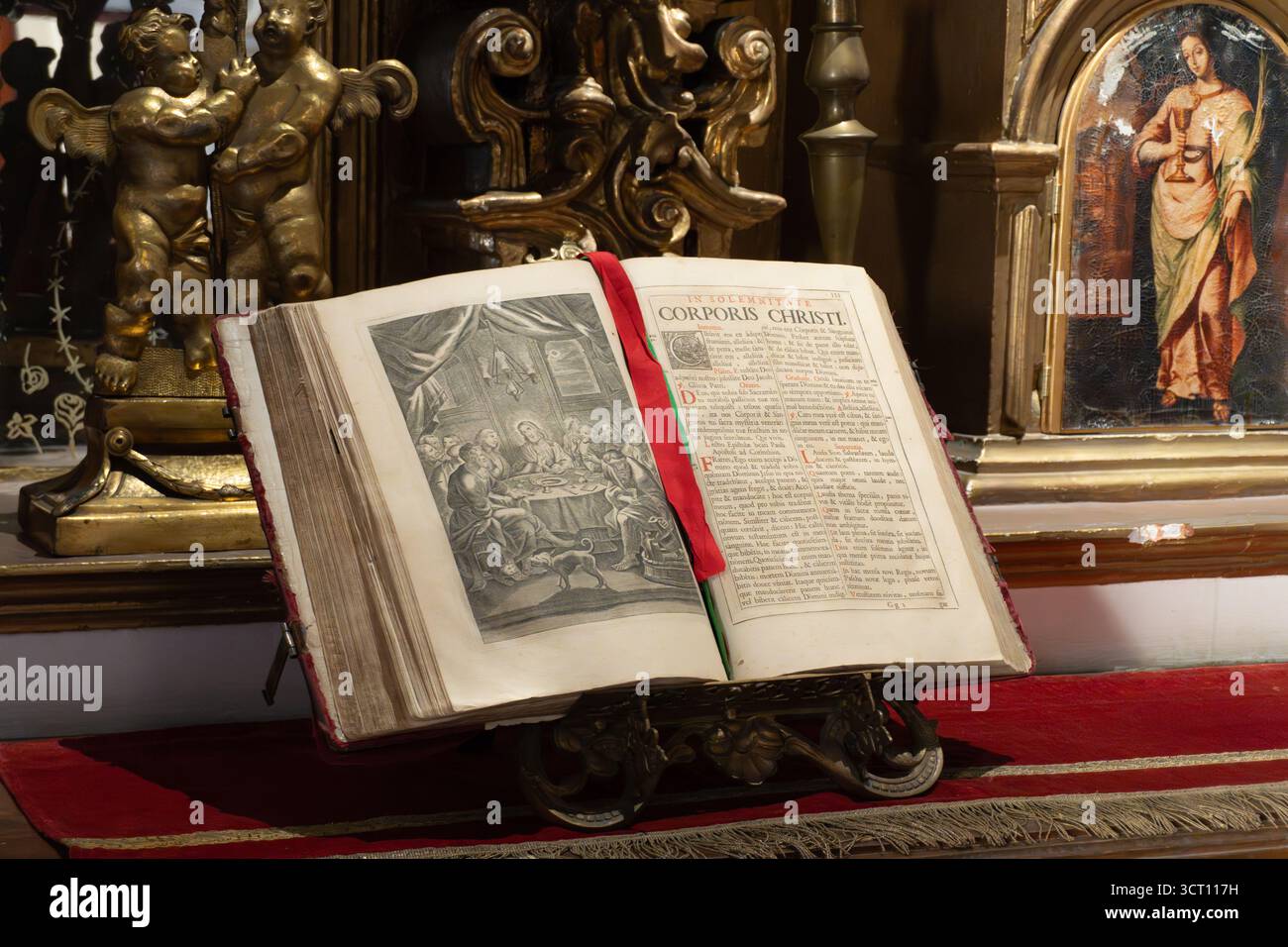 Un libro è aperto a una pagina con un nastro rosso. Il nastro è legato al libro, e il libro è su una tribuna. Il libro è vecchio e ha una cornice dorata. Città di Foto Stock