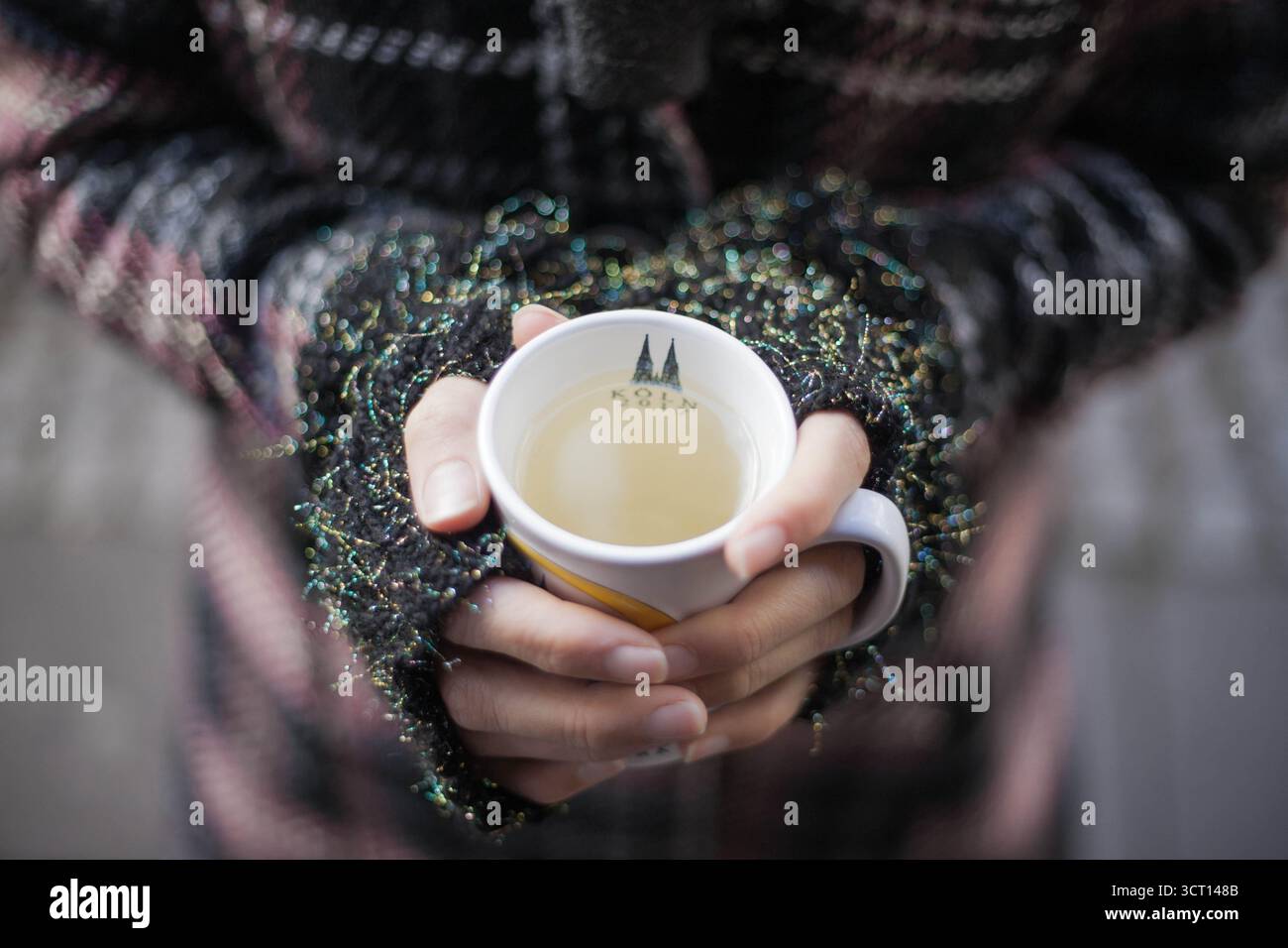 Primo piano su hans donna che regge una tazza di VIN brulé. Le mani delle donne tengono in mano una bevanda calda, indossano guanti senza dita e cappotto invernale. Mercatino di Natale. Foto Stock