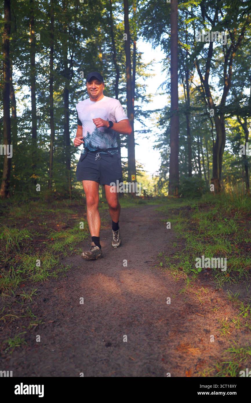 Uomo che corre attraverso Forest Trail Foto Stock