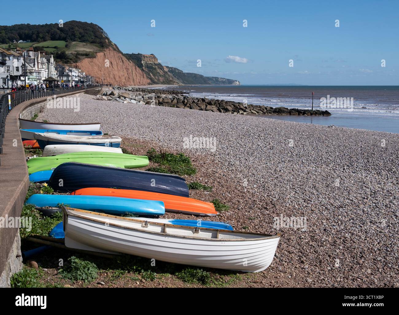 Barche a remi sulla riva di Sidmouth con le scogliere di sabbia rossa e la costa, Devon, Inghilterra. Foto Stock