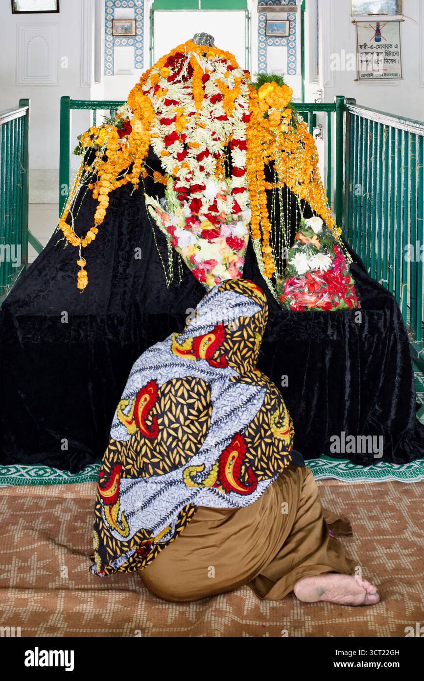Un devoto prega davanti a una tazia adornata di fiori all'interno del Dalan Hussaini, il principale sciita di Dhaka Imambara e centro dei rituali Muharram. Foto Stock
