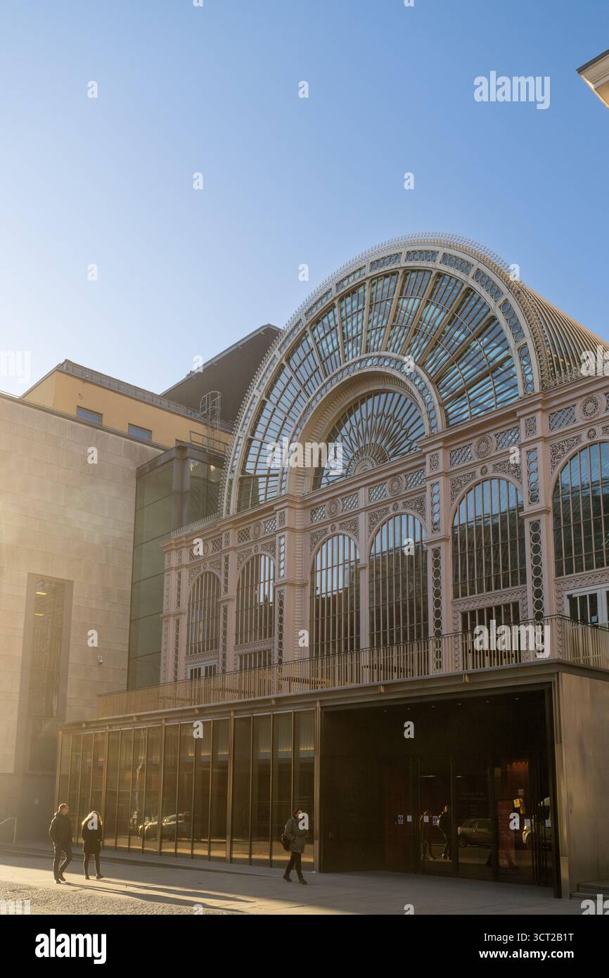 La gente passeggia accanto alla Royal Opera House di Londra, immersa nel caldo bagliore del sole che tramonta. Foto Stock