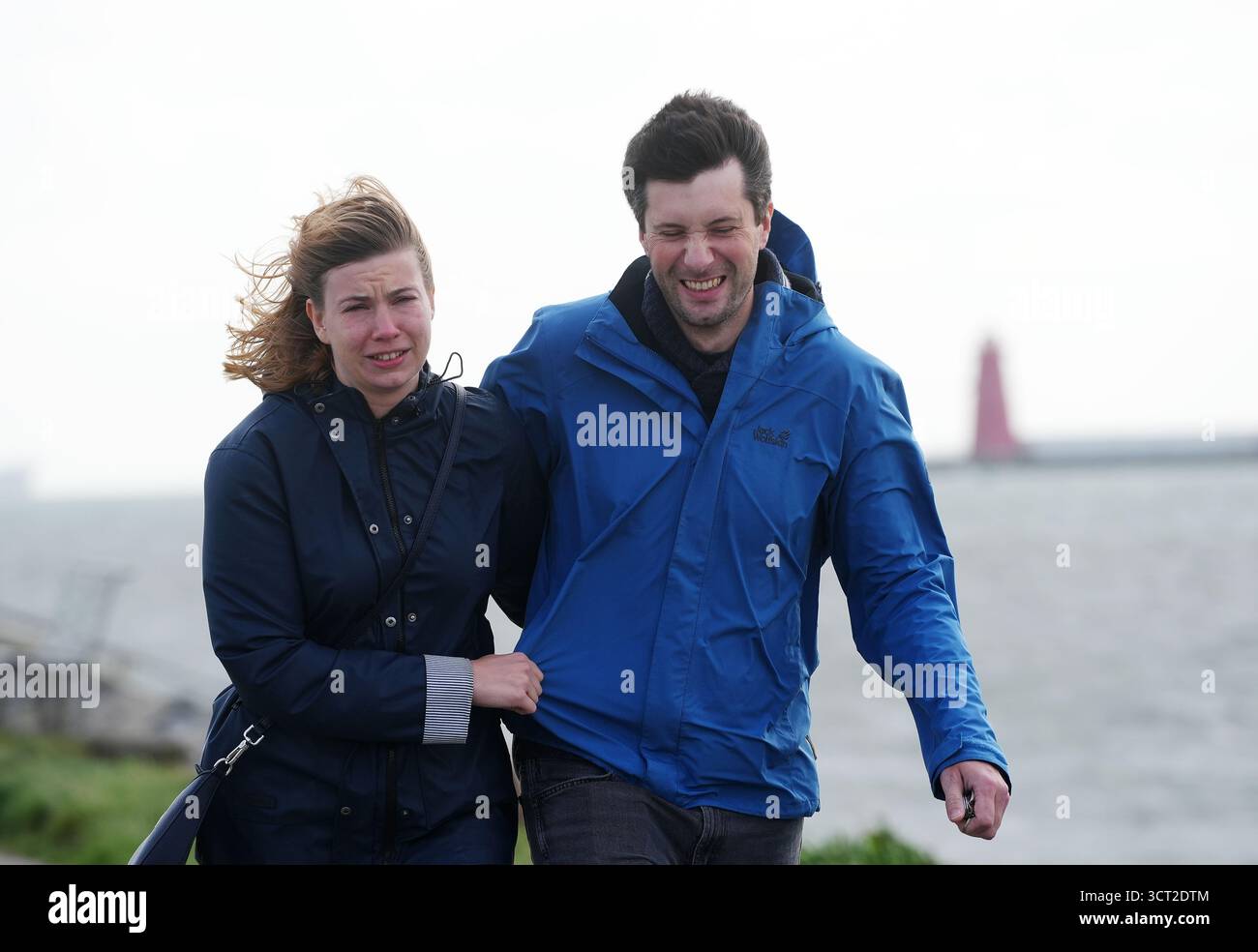 La gente lotta contro i forti venti sul Bull Wall di Dublino. Decine di migliaia di proprietà erano ancora senza energia, mentre sabato dopo la tempesta Amy ha colpito l'isola d'Irlanda è iniziata una ripulitura. Data foto: Sabato 4 ottobre 2025. Foto Stock