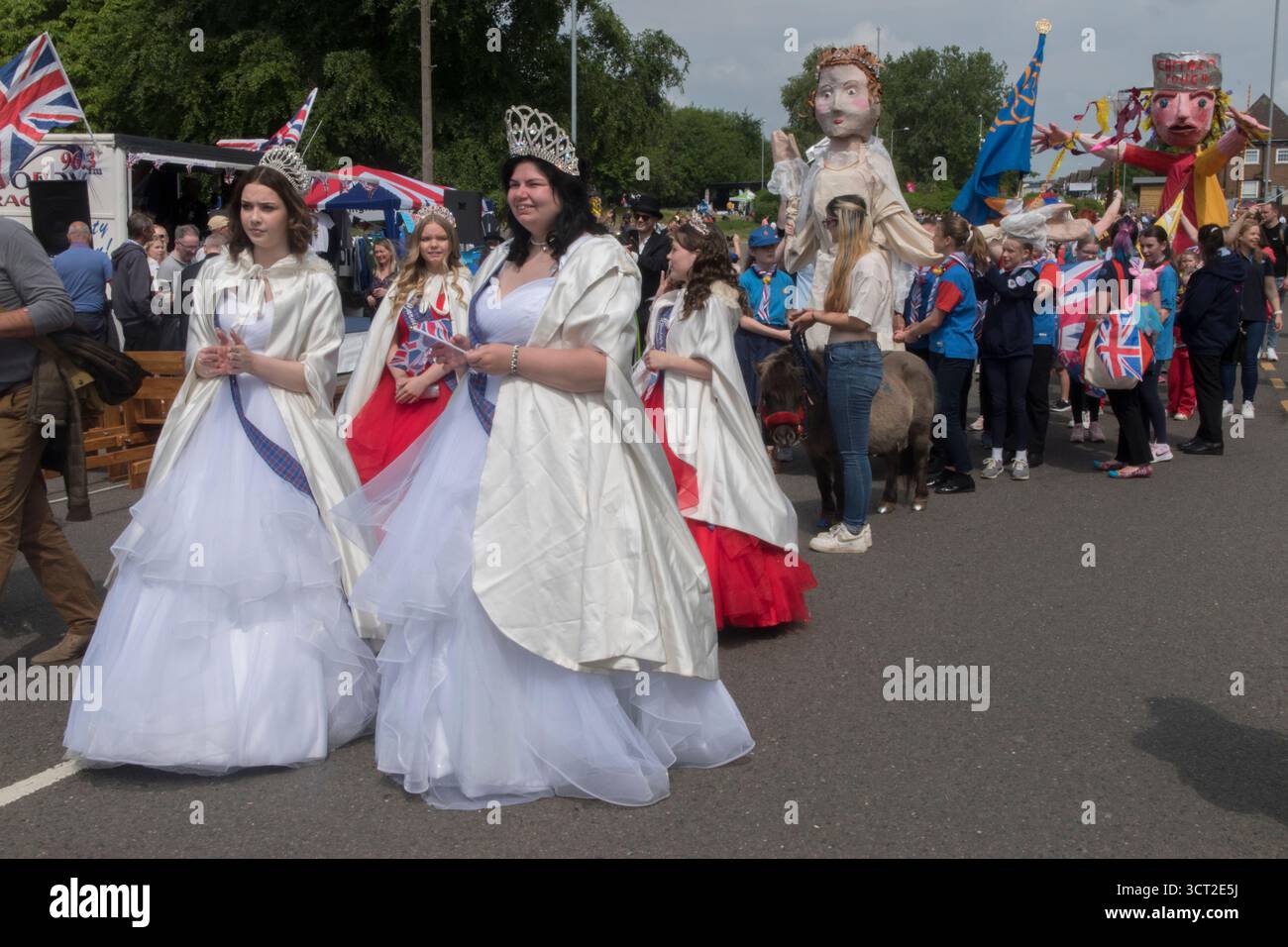 Processione storica del villaggio, sfilata intorno al vecchio villaggio di Corby, con gigantesche figure storiche di machie peppier associate a Corby. La regina Elisabetta i e il capitano Pouch. Due giovani donne di fronte rappresentano la Regina Elisabetta 1 e 2. Corby Pole Fair, Corby Old Village, Northamptonshire, Inghilterra 3 giugno 2022 2020s UK HOMER SYKES Foto Stock