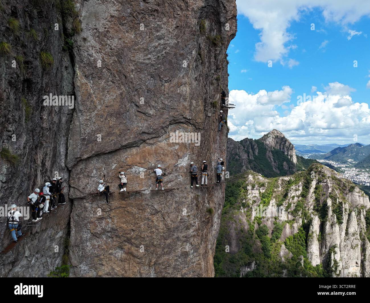 Pechino, Cina. 4 ottobre 2025. Una foto scattata con un drone il 4 ottobre 2025 mostra i turisti che vivono la via Ferrata, una forma di arrampicata assistita lungo cavi d'acciaio e pedemontari ancorati a pareti rocciose, in un punto panoramico a Yueqing, nella provincia dello Zhejiang della Cina orientale. Le destinazioni turistiche in tutta la Cina stanno assistendo a un'impennata di visitatori con l'inizio delle festività nazionali di otto giorni e del Festival di metà autunno del paese mercoledì. Crediti: CAI Kuanyuan/Xinhua/Alamy Live News Foto Stock