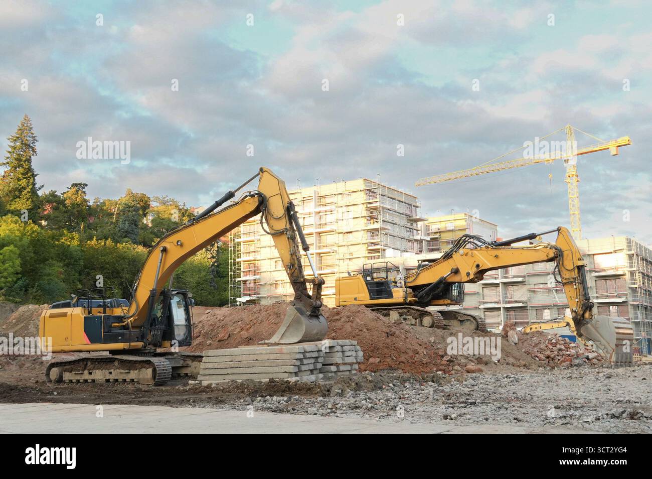 escavatore in un cantiere edile sullo sfondo di edifici a più piani Foto Stock
