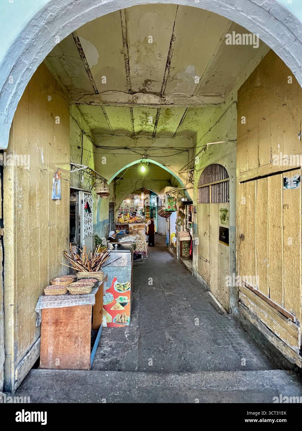 Vicolo a volta con venditori ambulanti e mura gialle nello storico mercato di Tangeri, Marocco - 3 ottobre 2025 Foto Stock