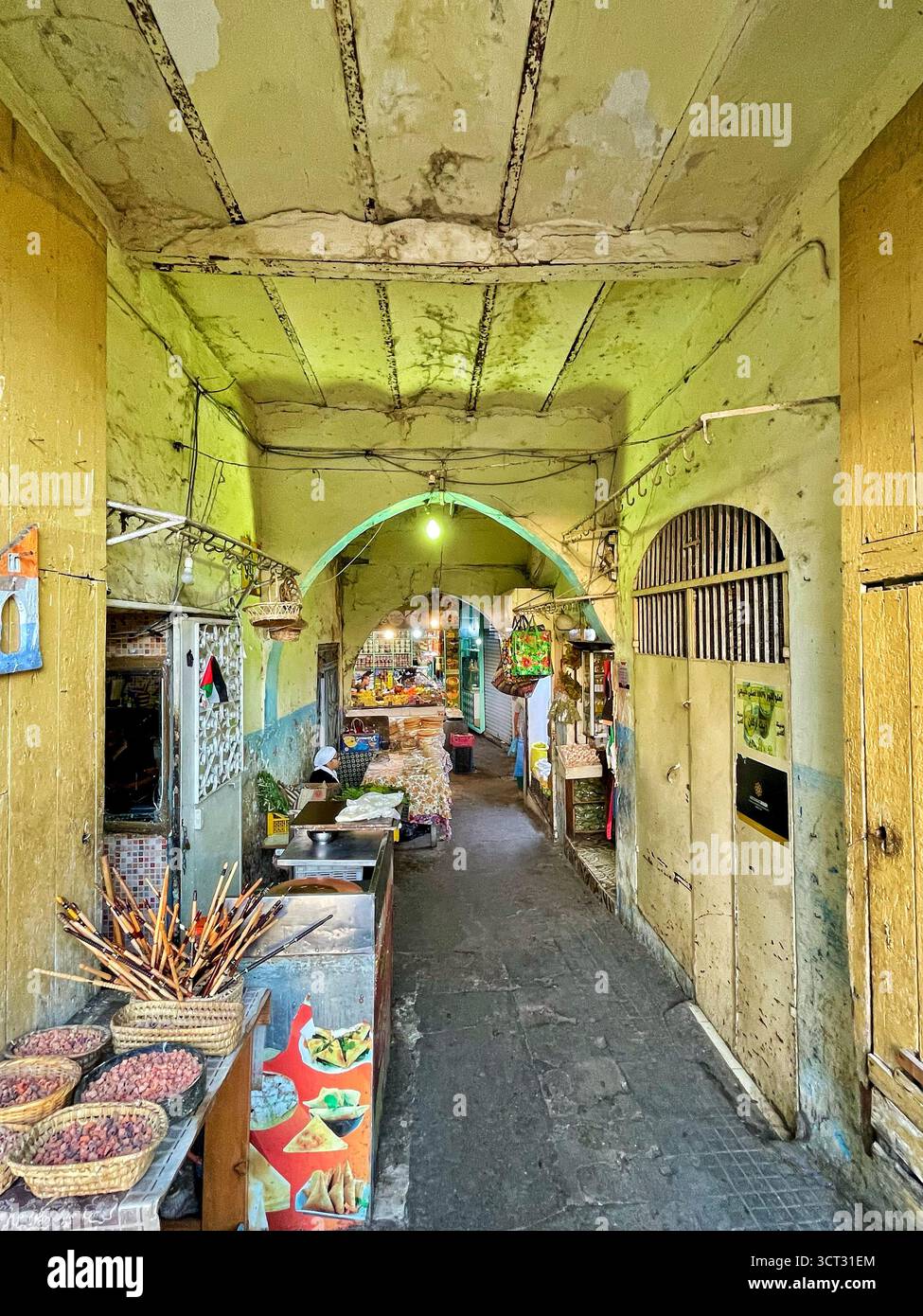 Vicolo a volta con venditori ambulanti e mura gialle nello storico mercato di Tangeri, Marocco - 3 ottobre 2025 Foto Stock