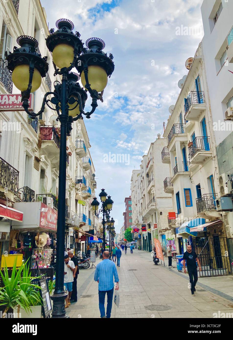 Vista sulla strada nel centro di Tunisi, Tunisia. Lampada a lampione decorata, pedoni e un mix di architettura moderna e tradizionale. Catturato il 22 settembre 2025. Foto Stock