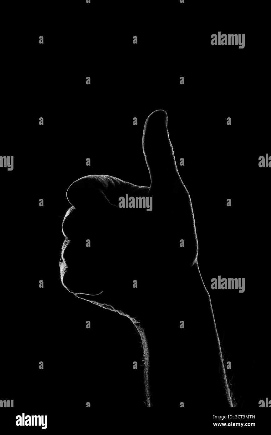 Il pollice di una mano alzata in chiaroscuro Foto Stock