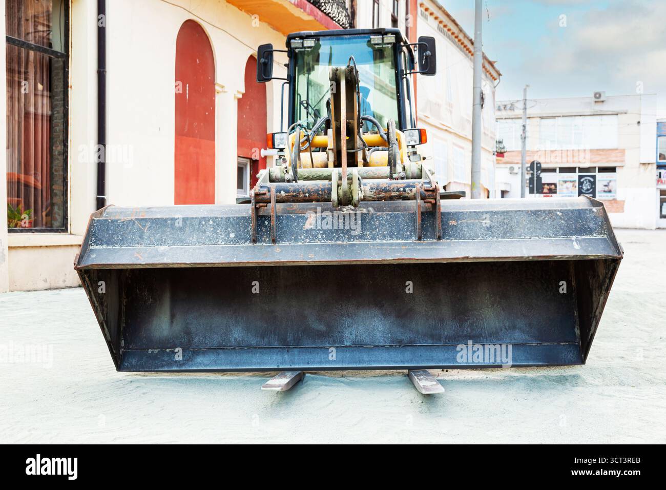 Un bulldozer con ruote gialle e benna anteriore si trova in città in un cantiere edile. Foto Stock