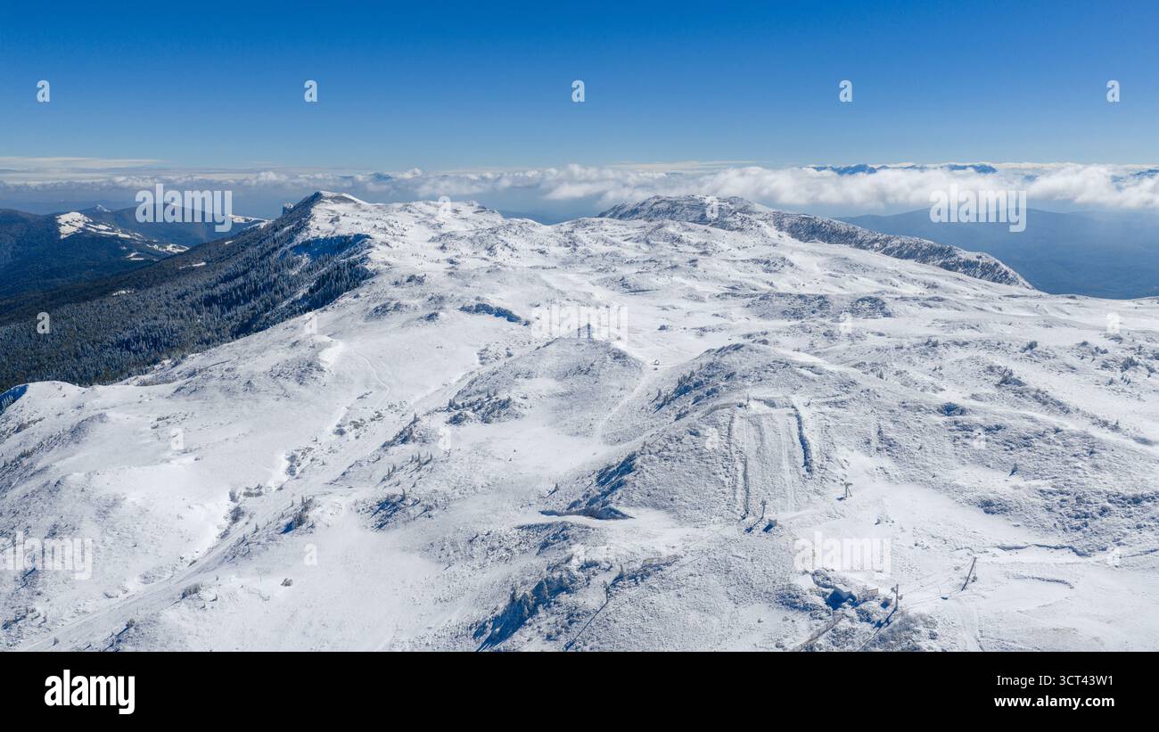 Panorama invernale mozzafiato del monte Jahorina e dell'area sciistica coperta di neve sotto il cielo azzurro Foto Stock