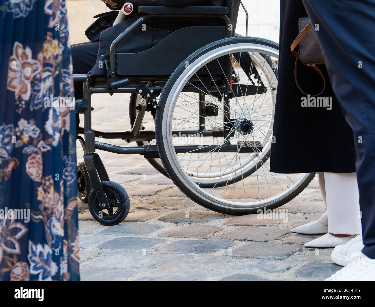 Sedia a rotelle tra le persone durante un evento, simbolo dell'inclusione, della diversità e dell'accessibilità nella vita di tutti i giorni. Foto Stock