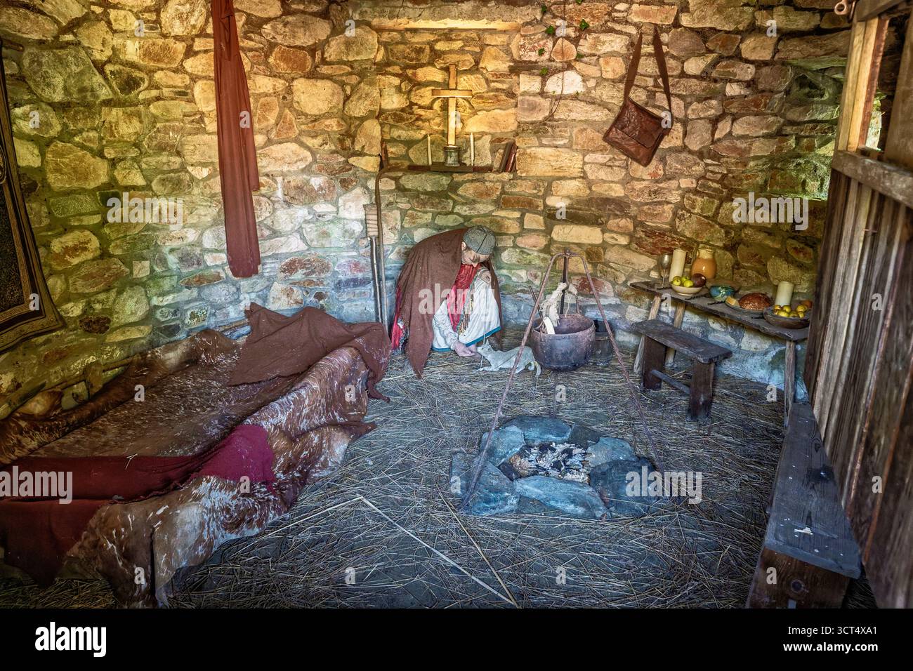 Vita monastica dei primi cristiani raffigurata con una figura di cera e una cella rustica di pietra all'Irish National Heritage Park Foto Stock