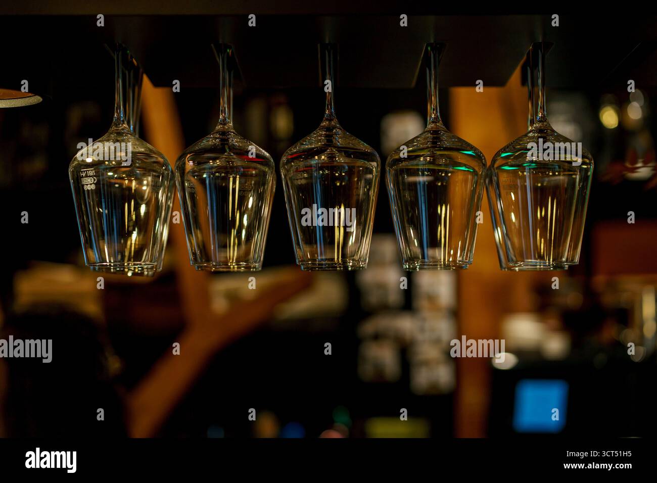 Molti bicchieri da vino sono appesi su un'asta sopra il bancone del bar. Stoviglie per bar e ristoranti Foto Stock