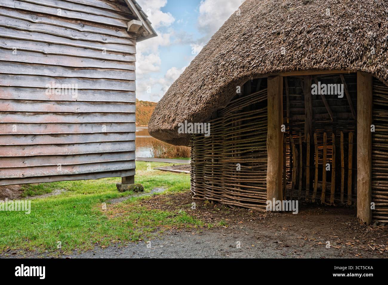 Ricostruzione di un insediamento norreno con una casa di rottami e un capannone di legname a contrasto, fiume sullo sfondo, inizio autunno, Wexford. Foto Stock