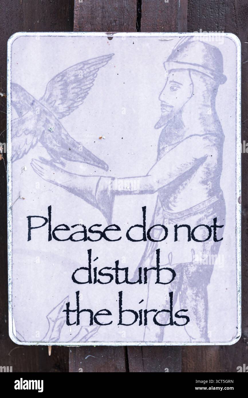 Cartello "Please do not disturb the Birds" (per favore non disturbare gli uccelli) con illustrazione medievale del falconiere all'Irish National Heritage Park, Wexford Foto Stock