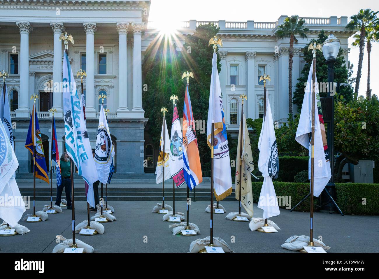 Mostra di bandiere tribali durante l'evento della giornata dei nativi americani della California al Campidoglio dello stato con un'esplosione di sole. Foto Stock