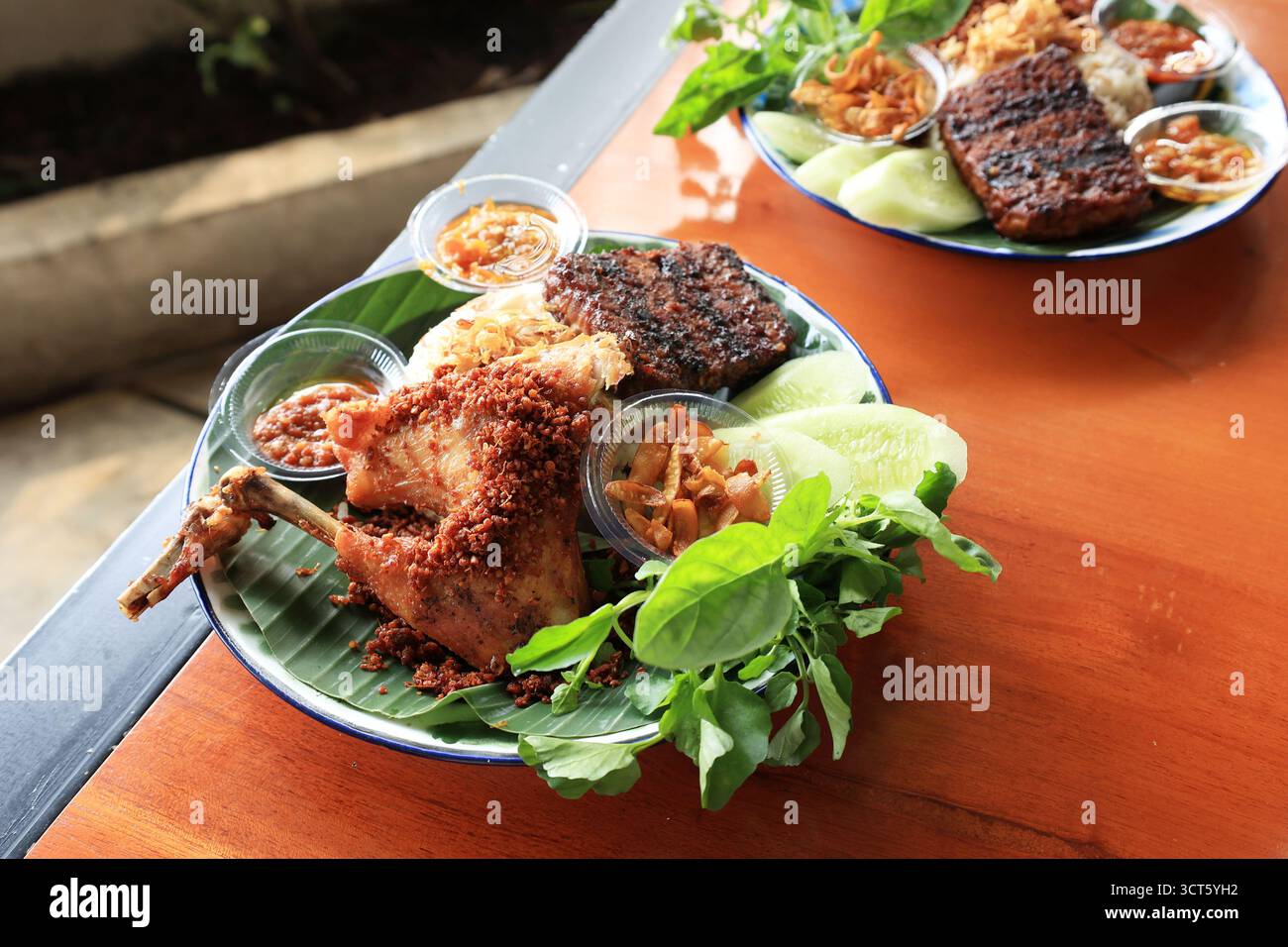 Ayam Goreng Rempah, pollo fritto con spezie aromatizzate e saporite. Servito con riso e Lalapan Foto Stock