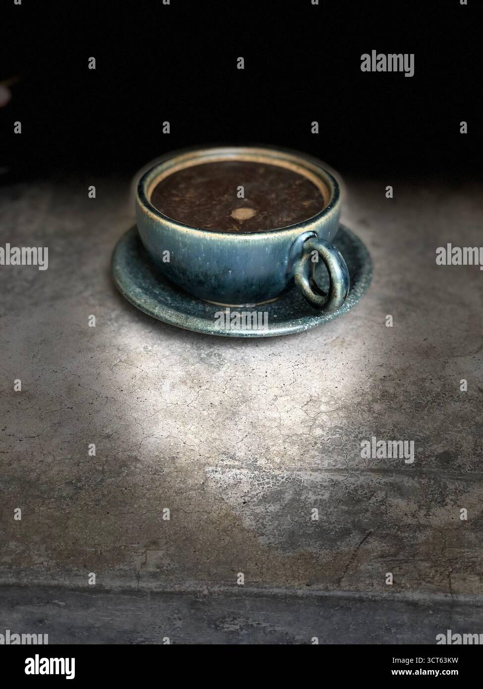 Tazza da caffè in ceramica su una superficie rustica in pietra con illuminazione soffusa, per creare una scena accogliente e minimalista. Foto Stock