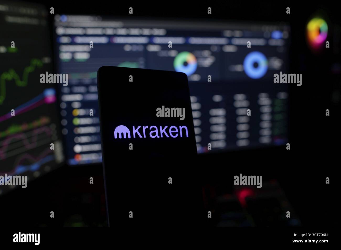 Smartphone con logo Kraken sullo schermo con grafici e dati finanziari Foto Stock