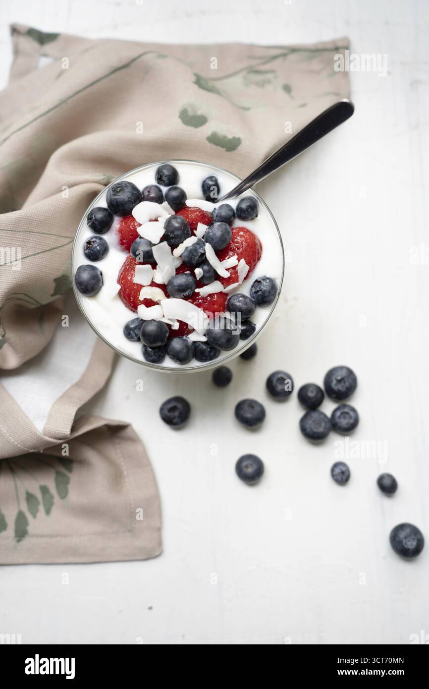 Yogurt con fragole fresche, mirtilli e pezzi di cocco Foto Stock