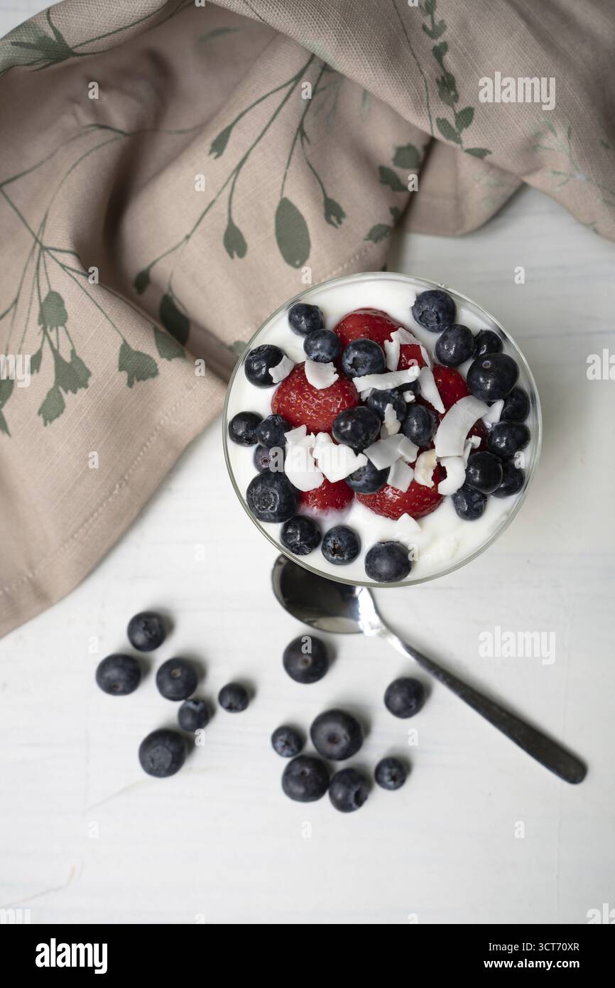 Yogurt con fragole fresche, mirtilli e pezzi di cocco Foto Stock