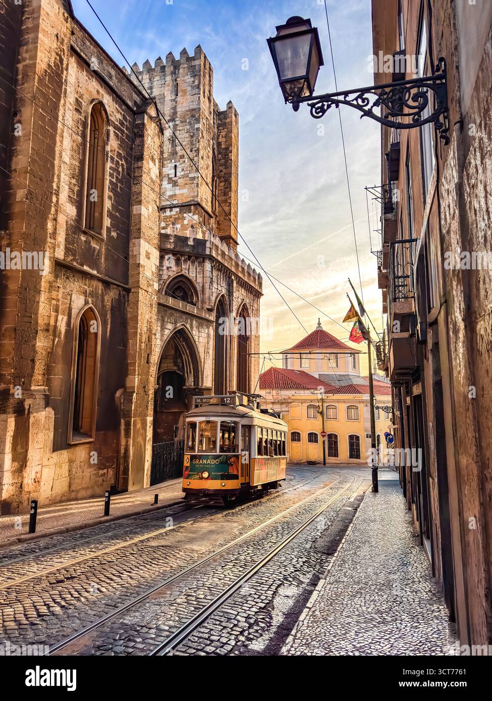 Lo storico tram 12 passa davanti alla cattedrale sé di Lisbona ad Alfama nella calda luce del pomeriggio. Foto Stock