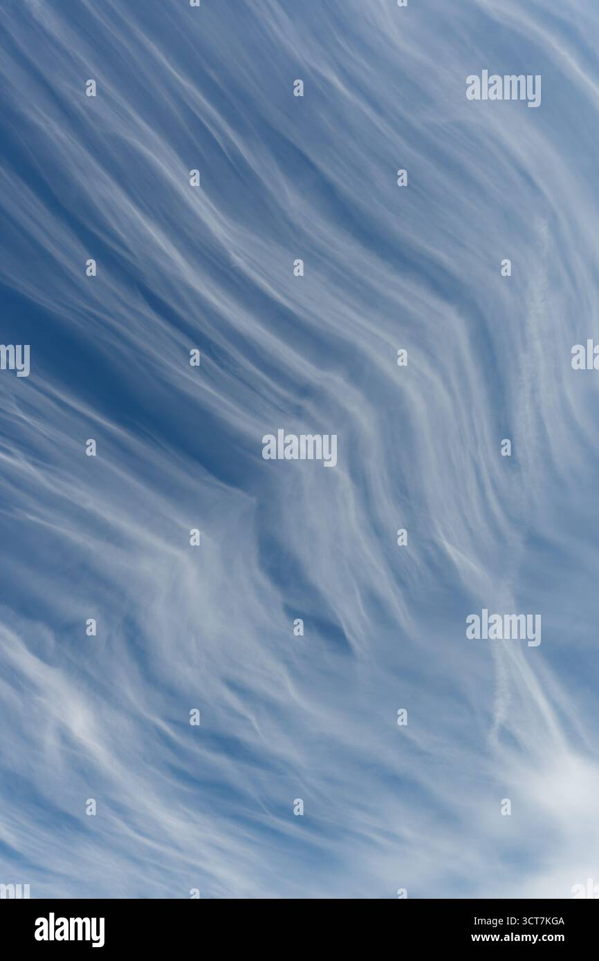 Formazione di nuvole alte linee ondulate contro un cielo blu che forma forme astratte Foto Stock